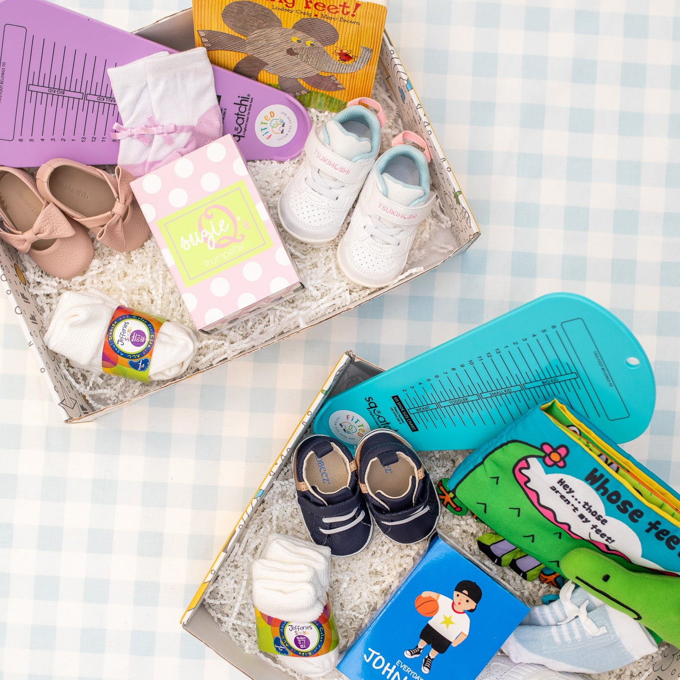 A collection of baby items neatly arranged in two boxes, including socks, shoes, a storybook, and other baby essentials.